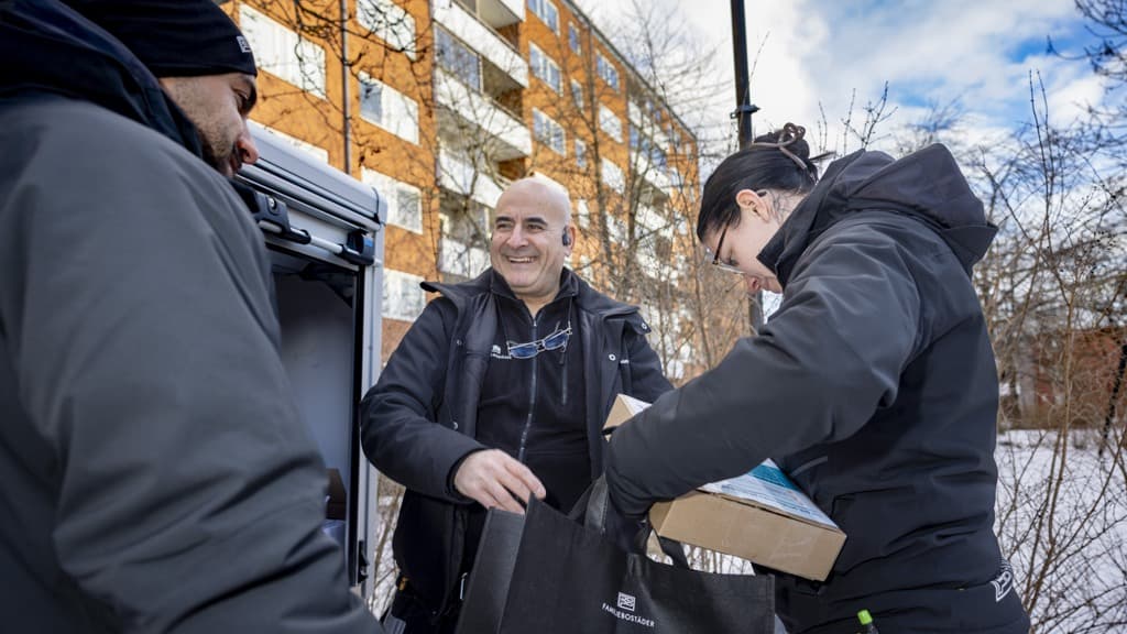 Två män och en kvinna som står bredvid varandra nära en byggnad.