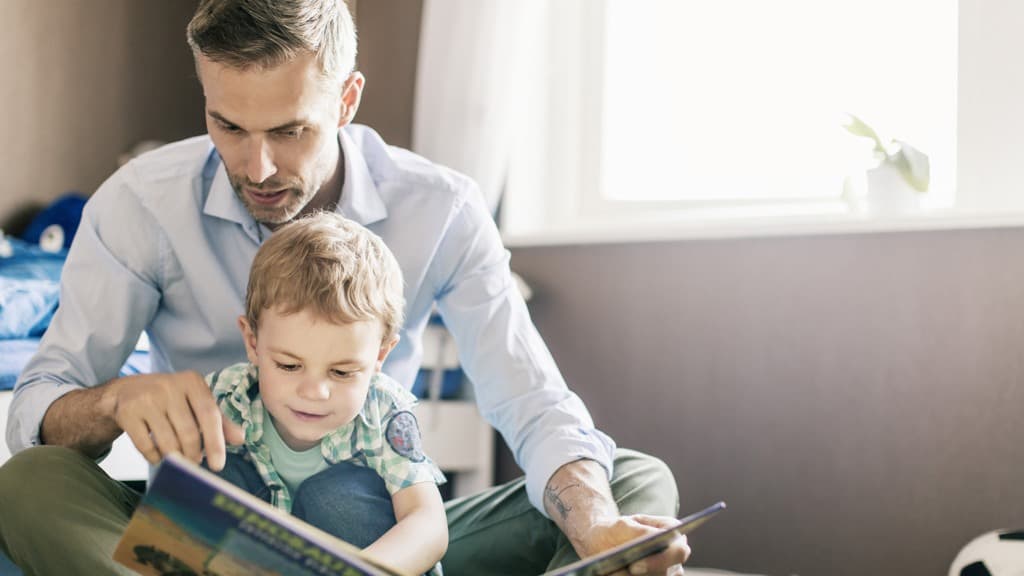 Man och en pojke sitter och läser en bok