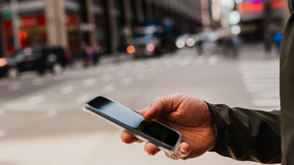 Handen på en man som håller i en mobiltelefon.