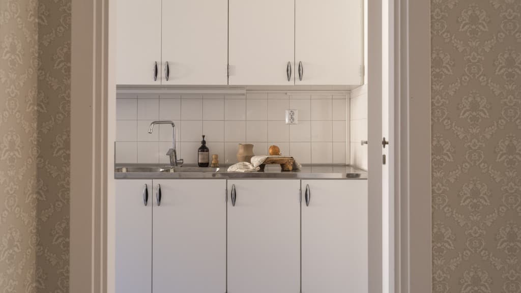 Ett kök med vita skåp och en diskho.