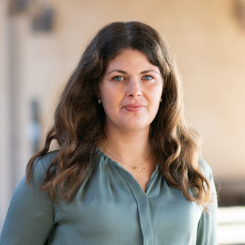 En kvinna med mörkt långt hår och grön skjorta.