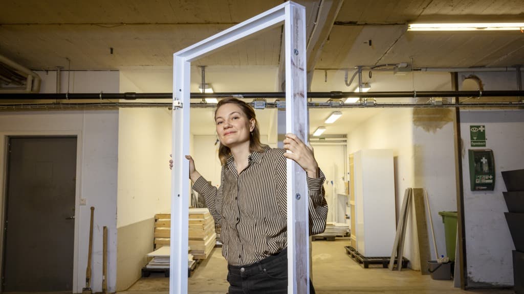 En kvinna står bakom en metallram i en lagerlokal.