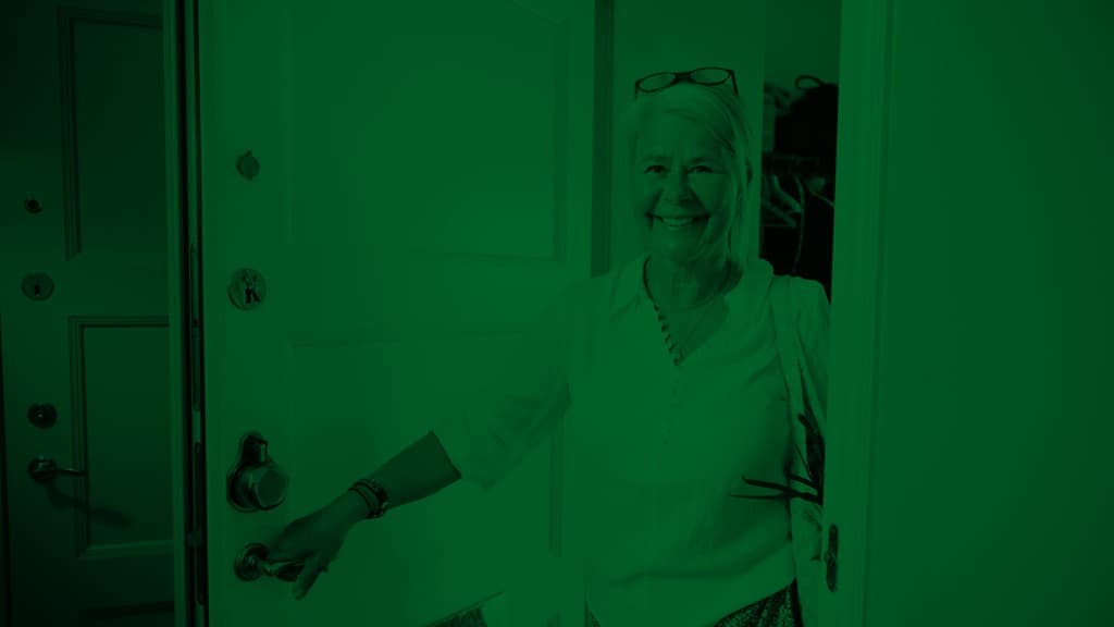 En kvinna öppnar en lägenhetsdörr.