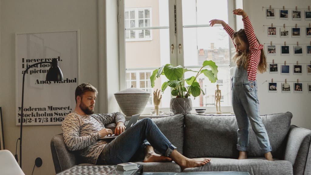 En man och ett barn sitter i en soffa i ett vardagsrum.