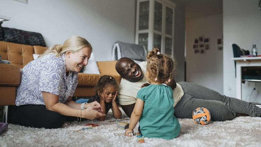 En grupp människor som sitter på golvet och leker med leksaker.