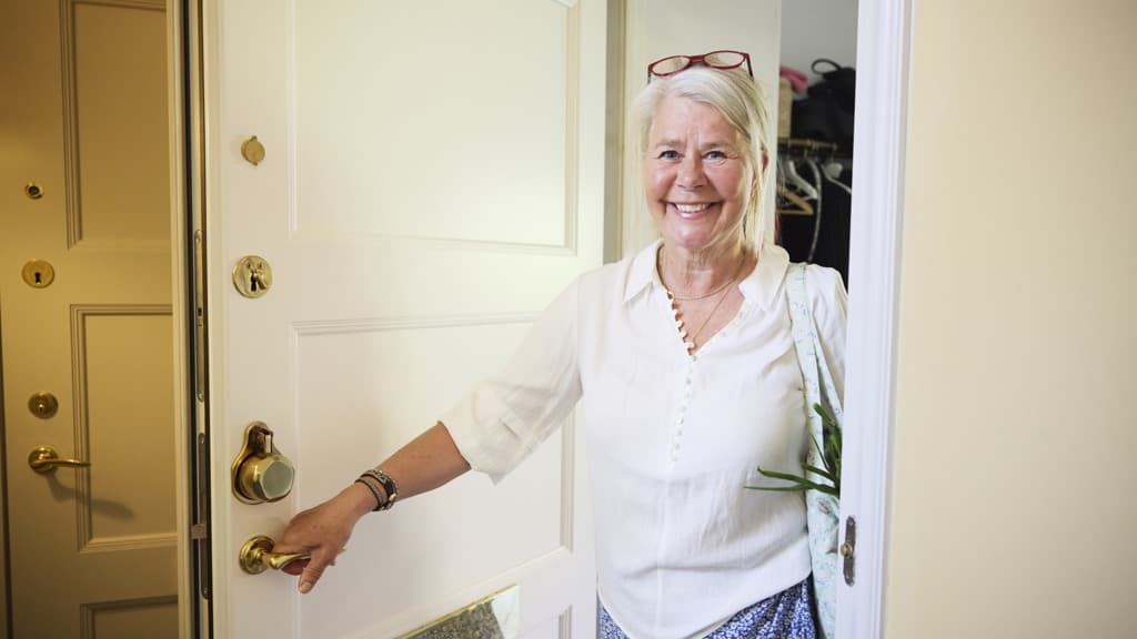 En kvinna står framför en vit dörr.