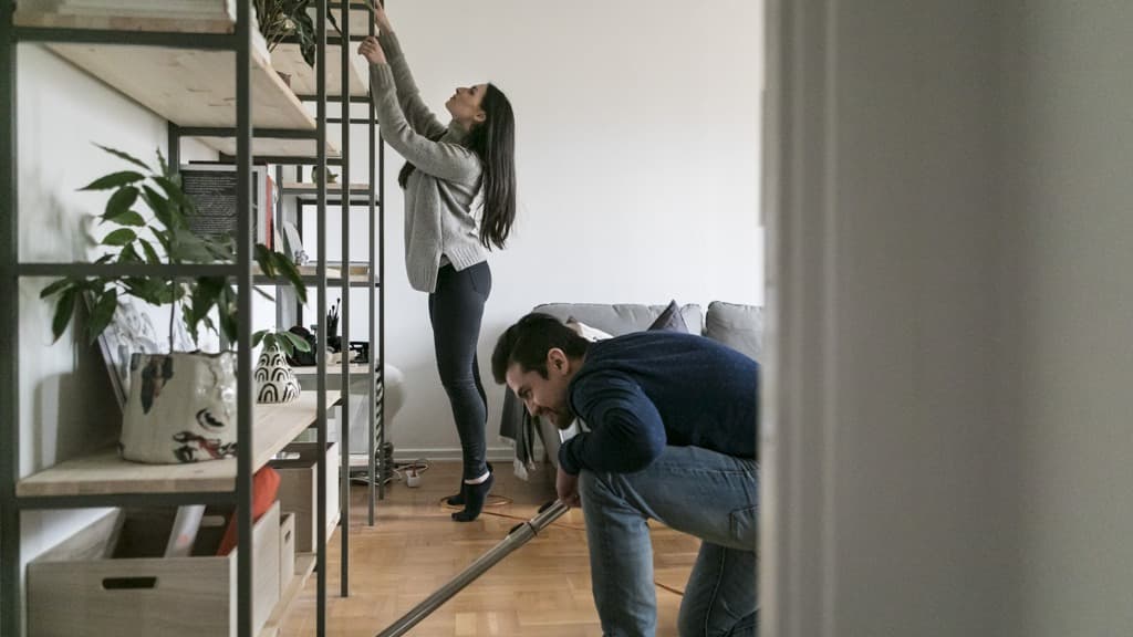 En man och en kvinna städar ett vardagsrum.