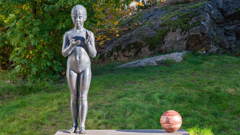 Konst i utomhusmiljö. Skulptur av ett barn som håller upp händerna runt en osynlig boll.