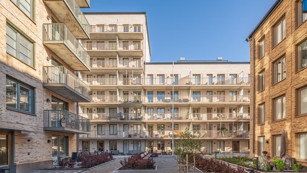 Bild från gården på Kraftcentralen i Älvsjöstaden. Gula tegelhus med balkonger mot gården. 