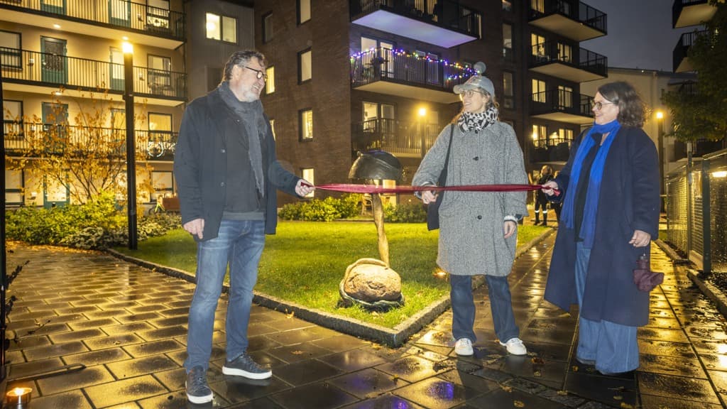 En grupp människor som håller ett band framför en byggnad.