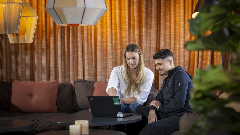 En man och en kvinna sitter i en soffa och tittar på en bärbar dator.