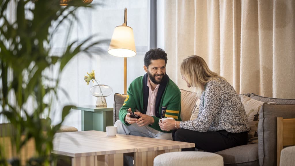 En man och en kvinna sitter i en soffa och pratar.