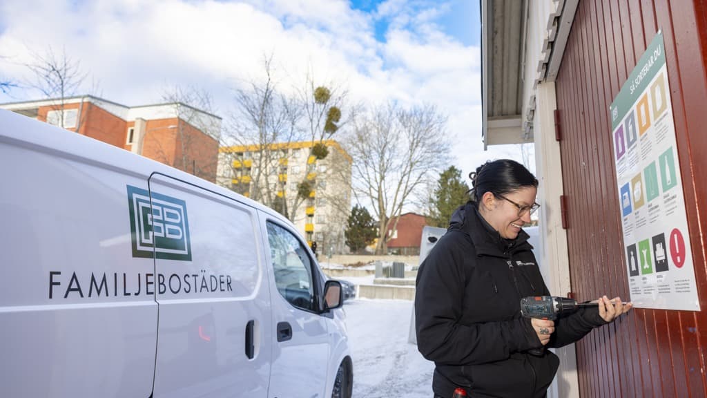 En kvinna sätter upp en skylt på en vägg.