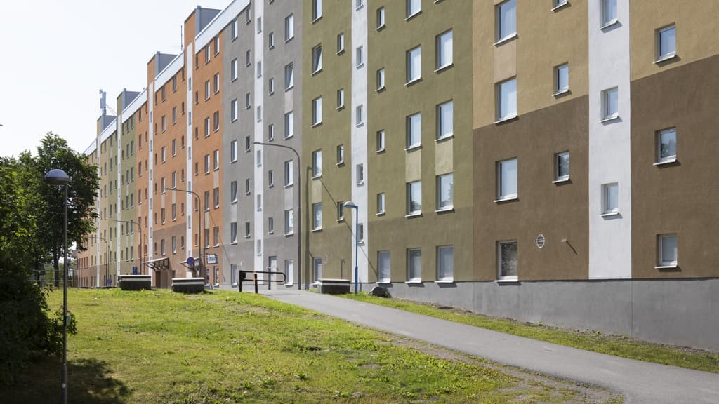 En gräsyta framför en rad flerfärgade hyreshus.
