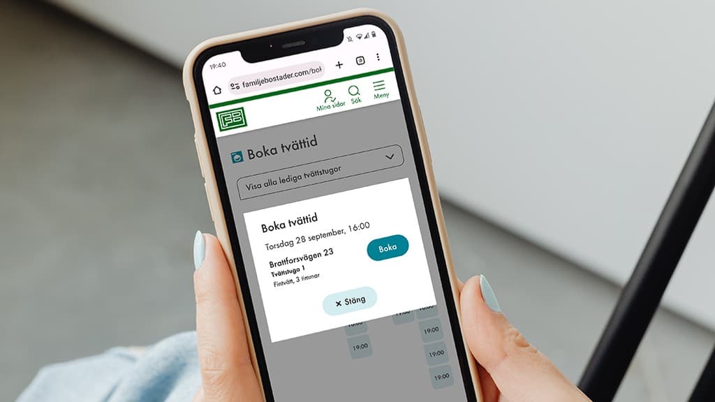 En person som håller en mobiltelefon i handen och håller på att boka tvättid på Mina sidor.