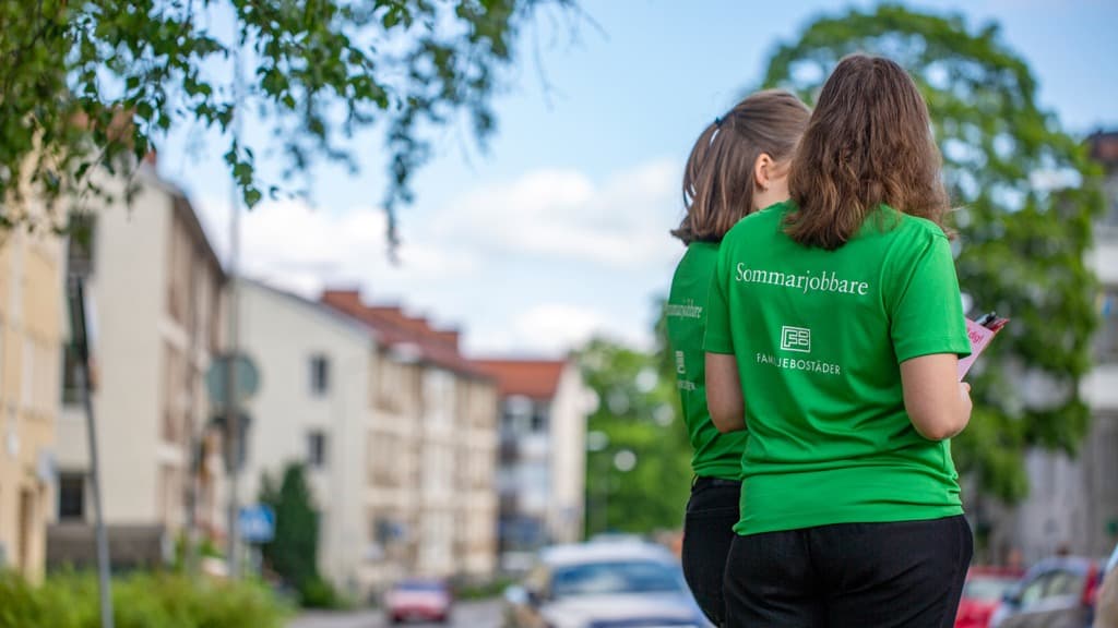 Två personer i gröna tröjor på stadsgata.