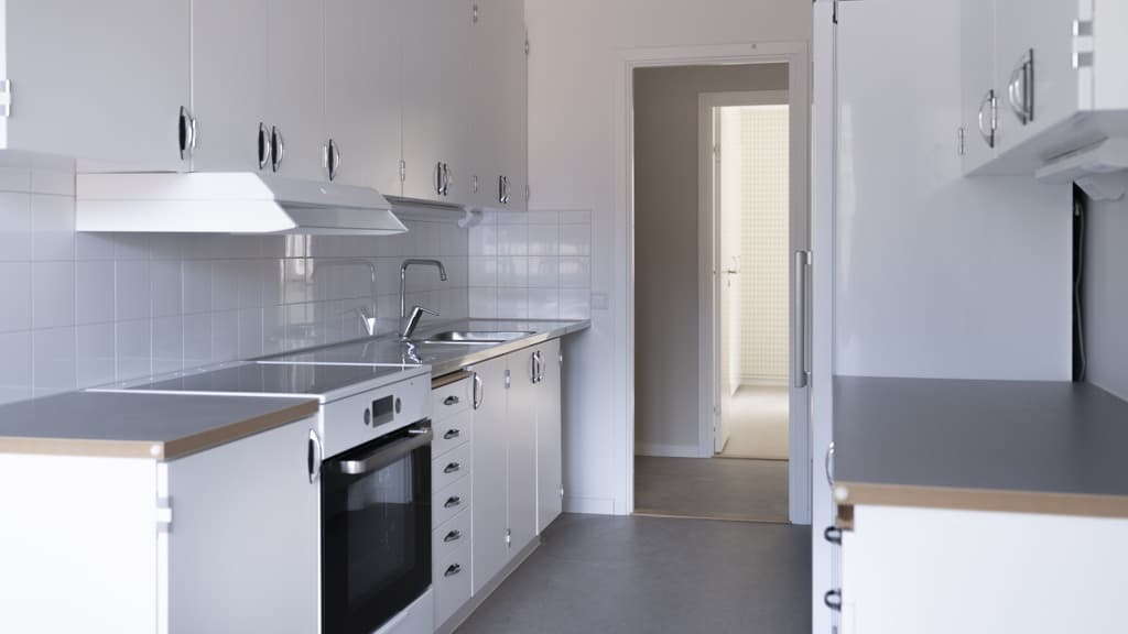 Ett kök med vita skåp och en spishäll med ugn.