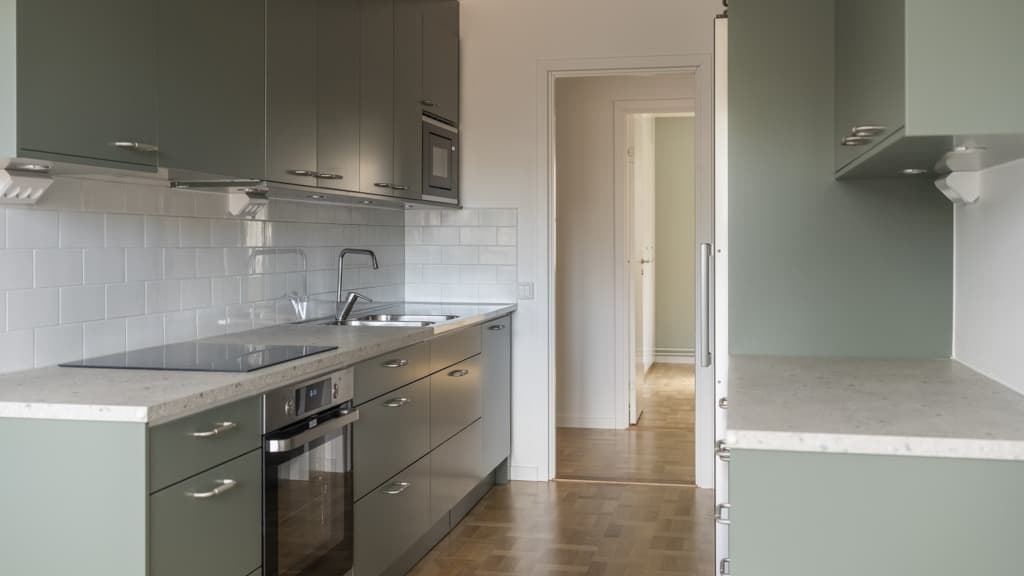 Ett kök med gröna luckor med en spishäll och ugn.