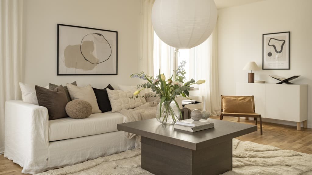 Ett vardagsrum med en vit soffa och ett soffbord.