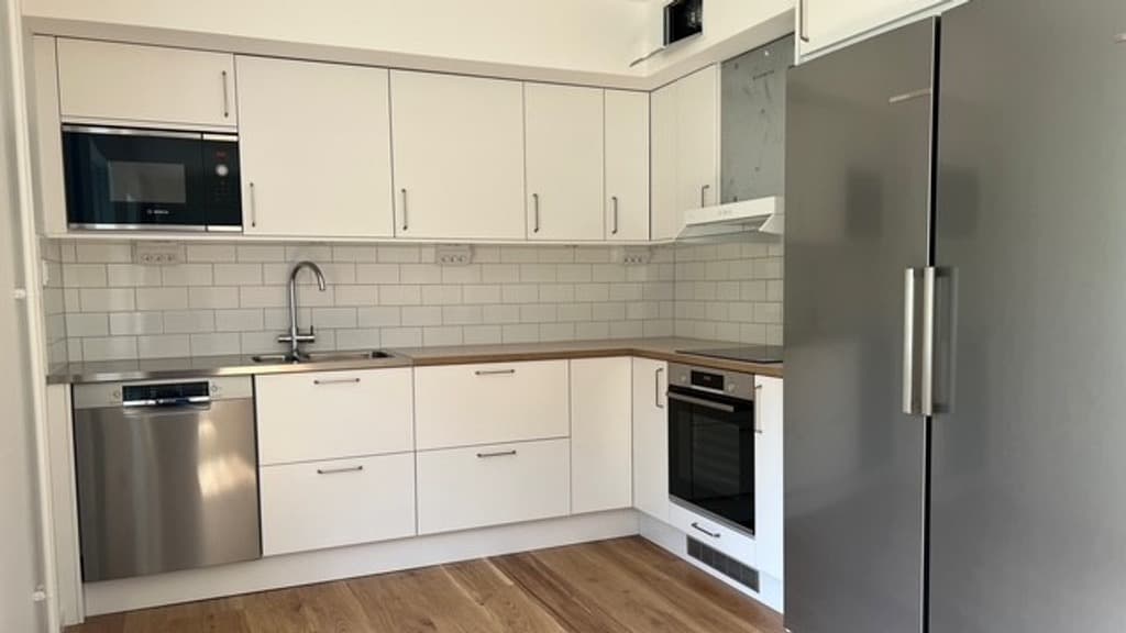 Ett kök med kylskåp, spis, diskho och kyl/frys.