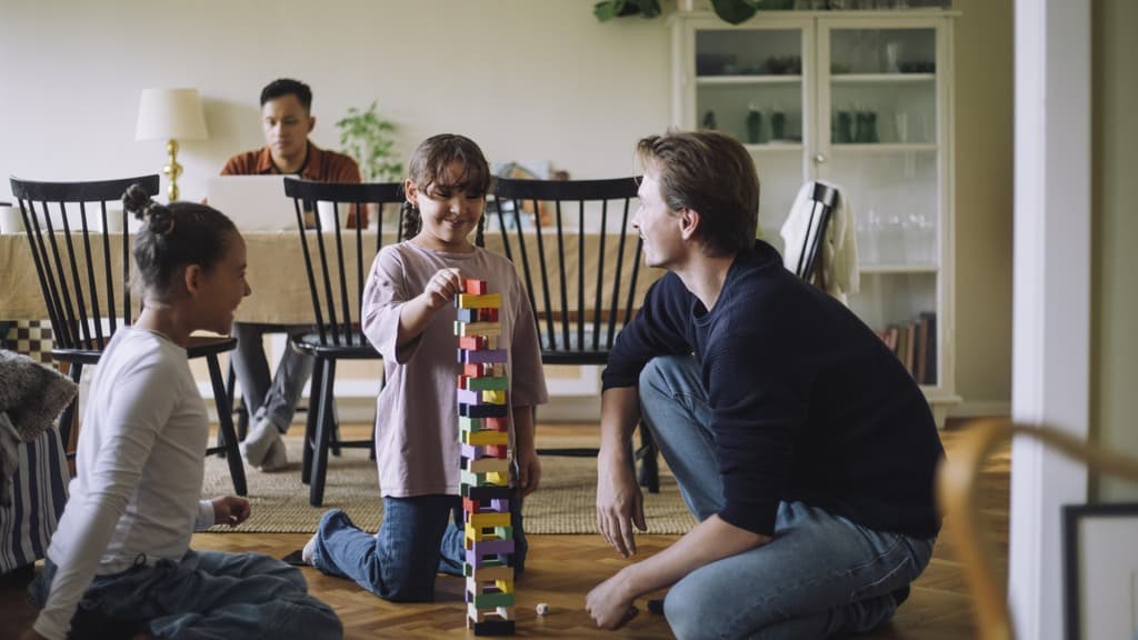 En grupp människor som sitter på golvet och leker med klossar.