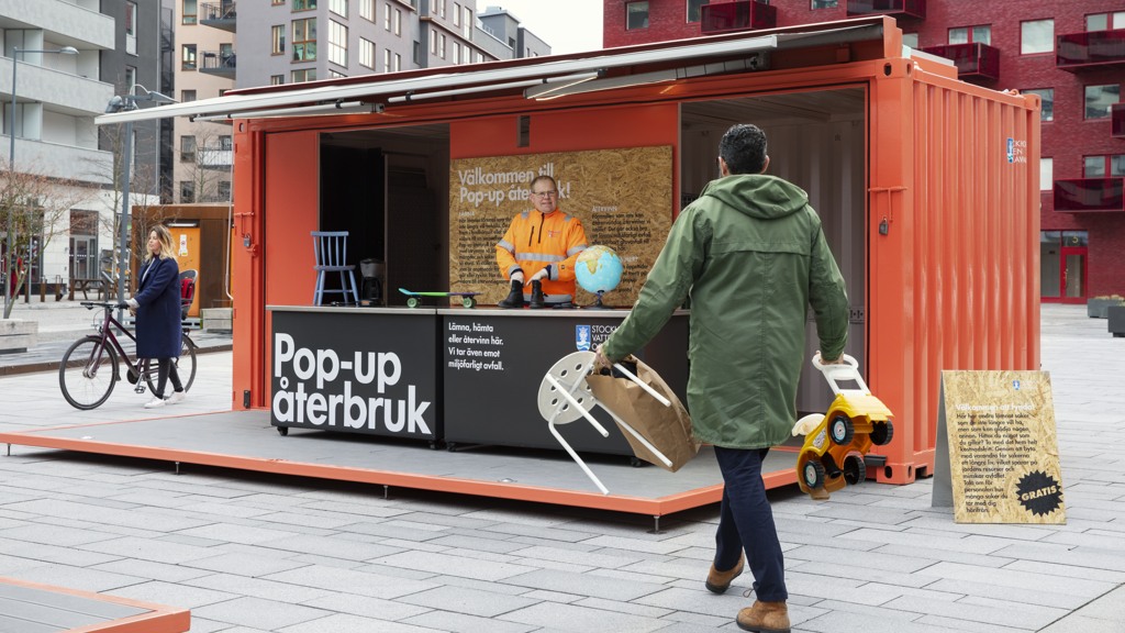 Containern Pop-up återbruk med personal bakom disken och en besökare som ska lämna saker till återbruk