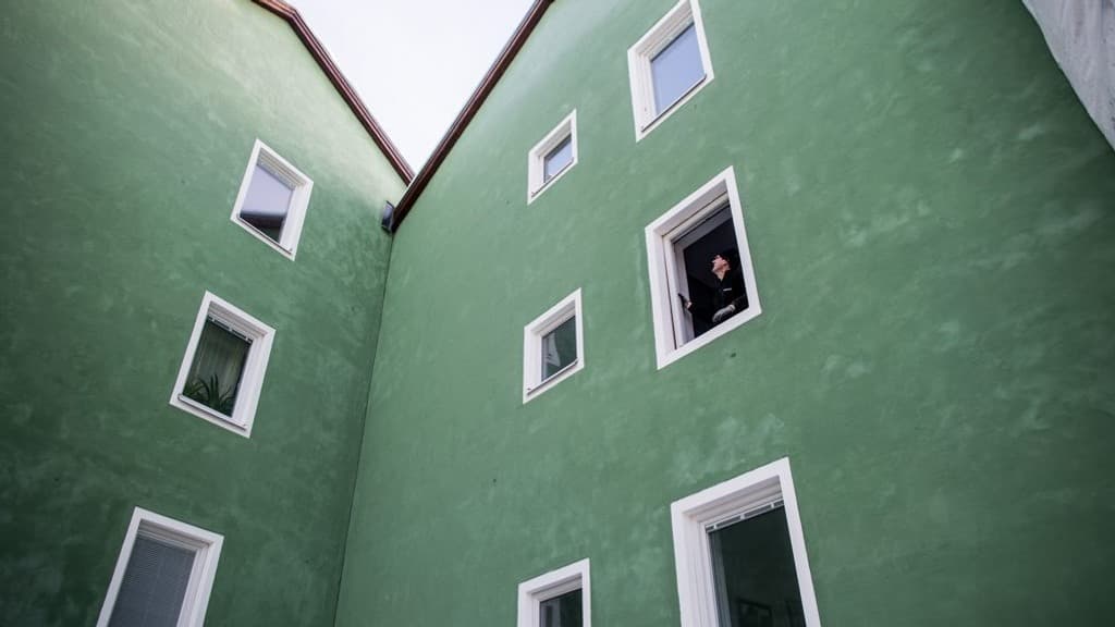 Grönt trevåningshus med byggställning.